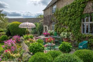 einen Garten vor einem Gebäude mit einem Tisch und einem Sonnenschirm in der Unterkunft Pytts House Boutique Bed & Breakfast in Burford