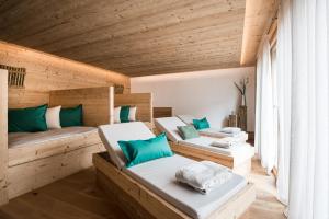 two beds in a room with wooden walls at Les Dolomites Mountain Lodges in San Martino in Badia