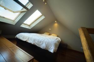 a attic bedroom with a bed with two windows at Apartament Nowy Świat in Warsaw