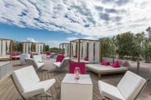 d'une terrasse avec des tables et des chaises blanches et un ciel nuageux. dans l'établissement Oz'Inn Hôtel & Spa, au Cap d'Agde