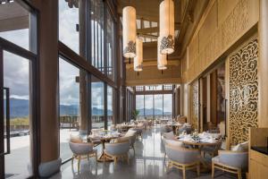 a dining room with tables and chairs and large windows at Banyan Tree Hotel Huangshan-The Ancient Charm of Huizhou, a Paradise in Huangshan