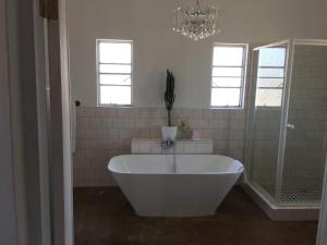 a white bath tub in a bathroom with a chandelier at Conductor's Inn in Tsumeb