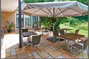 een patio met tafels en stoelen en een parasol bij Hotel BonaMari in Salzgitter
