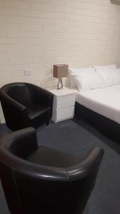 - une chambre avec un lit et une chaise à côté d'un lit dans l'établissement Lockleys Hotel, à Adélaïde