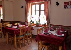 uma sala de jantar com mesas e cadeiras com toalhas de mesa vermelhas em Határ Csárda Panzió em Bajánsenye