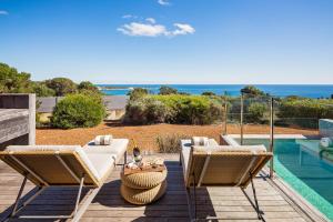 eine Terrasse mit einem Tisch, Stühlen und Meerblick in der Unterkunft Injidup Spa Retreat in Yallingup