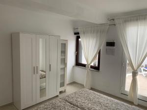 チャルコ・デル・パロにあるApartment Luna Nudist Placeの白いキャビネットと窓付きのベッドルーム1室