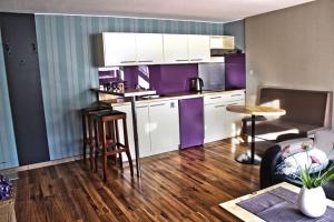 a kitchen with purple and white cabinets and a living room at Ferienwohnungen "Am Mühlteich" in Radeburg