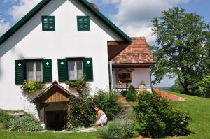 um homem sentado em frente a uma casa em s´ Kellerstöckl em Loipersdorf bei Fürstenfeld