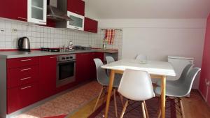 a kitchen with red cabinets and a white table and chairs at Guesthouse Una 1 Bihac in Bihać