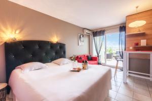 a bedroom with a large white bed with a black headboard at Résidence Hôtelière Natureva & Spa in Cap d'Agde