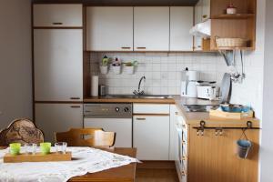 una pequeña cocina con armarios blancos y una mesa en Haus am Rötenberg en Grafenhausen