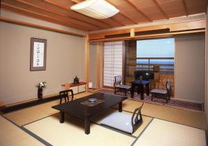a living room with a table and chairs and a large window at Hakusen in Yonago