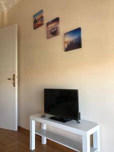 Une télévision à écran plat est installée au-dessus d'une table blanche. dans l'établissement Del Mar Apartments II, à Agia Triada