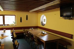 Un restaurante con mesas y sillas de madera y un televisor de pantalla plana. en Outdoor Zentrum Allgäu- Hostel, en Bihlerdorf