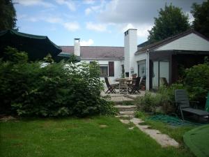 un patio con una casa con mesa y sillas en B&B Les Bergers, en Braine-lʼAlleud