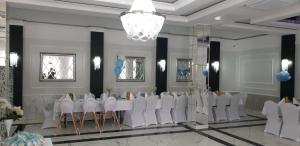 a banquet hall with white tables and chairs and a chandelier at Zacisze in Sokółka