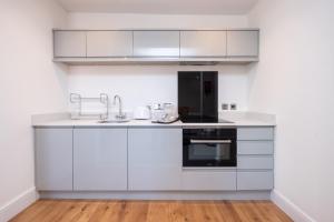 eine Küche mit weißen Schränken und einem Waschbecken in der Unterkunft Elm – Three Tuns Apartments in Pettistree