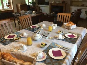 a table with a breakfast of bread and orange juice at La Musardine en Vexin in Omerville