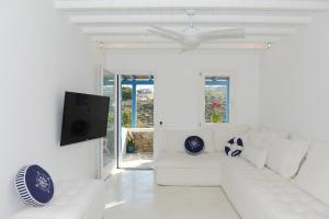 sala de estar blanca con sofá blanco y TV en Luxury White Maisonette, en Kalafatis