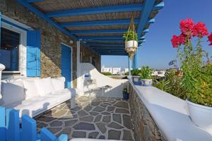 un balcón con muebles blancos y flores rojas en Luxury White Maisonette, en Kalafatis