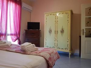 una camera con letto e cassettiera con tende rosa di Il Tuppo - al centro in cima a Messina