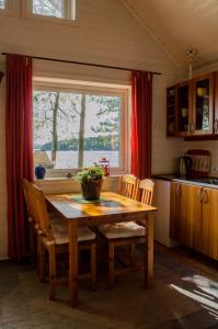 uma cozinha com uma mesa e cadeiras de madeira e uma janela em Strandstuga em Tämta