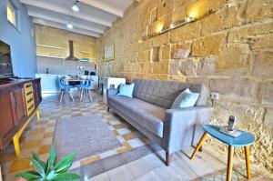 a living room with a couch and a stone wall at Eight Point Living 6B in Birgu