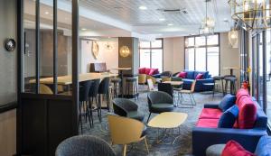 a lobby with chairs and tables and a bar at Hôtel National in Lourdes