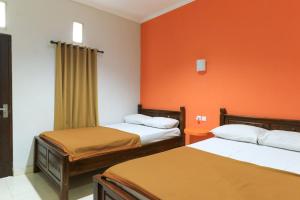 Pokój z 2 łóżkami i pomarańczową ścianą w obiekcie Hotel Warta Putra w mieście Denpasar