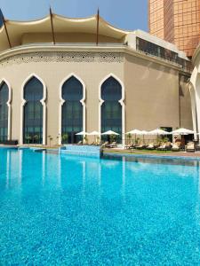 uma grande piscina com água azul em frente a um edifício em Bab Al Qasr Hotel em Abu Dhabi