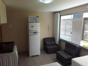 a room with a refrigerator and a chair and a window at Studio 208 - Perto UNB in Brasília