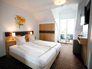 ein Hotelzimmer mit einem großen Bett und einem TV in der Unterkunft Hotel Diana in Pörtschach am Wörthersee