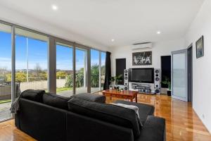 a living room with a black couch and a tv at BENGALEE EXECUTIVE TOWNHOUSE- MODERN & STYLISH in Mount Gambier