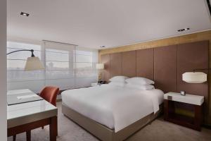 a bedroom with a large white bed and a desk at Grand Hyatt Taipei in Taipei