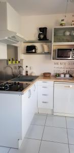a kitchen with white cabinets and a sink at logement ensoleillé in Cardet