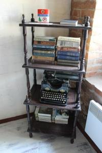 una estantería de libros con una pila de libros y una máquina de escribir en Hostel v Dnepropetrovske Grunge en Dnipró