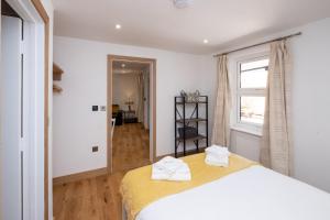 a bedroom with a bed with two towels on it at Weeping Willow – Three Tuns Apartments, Pettistree in Pettistree