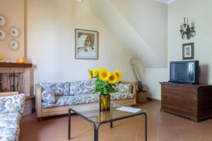 a living room with a couch and a vase with a sunflower at Poggio Vaccaio Casa Tramonto in Binami
