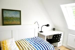 a bedroom with a bed and a desk with a lamp at Juteshus in Tating