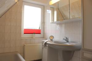 a bathroom with a sink and a window and a tub at Ferienhaus Wiedingharde I in Tating