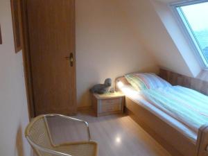 a small bedroom with a bed and a chair at Hof Peters in Tating