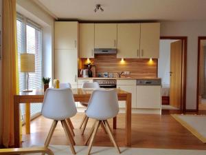 a kitchen with a wooden table and white chairs at Ferienwohnung am Seezeichen in Böhl