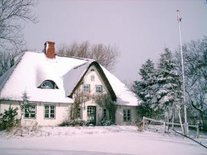 uma casa com neve no telhado no quintal em Gästehaus Andresen-Warft em Tating