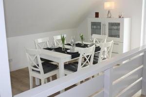 a white dining room with a white table and white chairs at Haus Deichblick in Vollerwiek