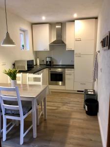 a kitchen with white cabinets and a table and chairs at Bauernhof Steffens in Tating