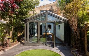 a glass greenhouse in a garden with a table at The Madras Cottage - Bright 3BDR Home with Garden in Cambridge