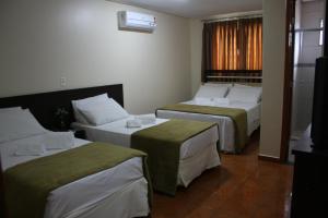 um quarto de hotel com duas camas e uma janela em Pinheiros Hotel em Goiânia