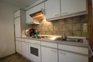 a kitchen with white cabinets and a sink at Ferienwohnung Remuß in Garding