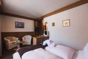 um quarto de hotel com duas camas e uma cadeira em Hotel Catinaccio em Vigo di Fassa